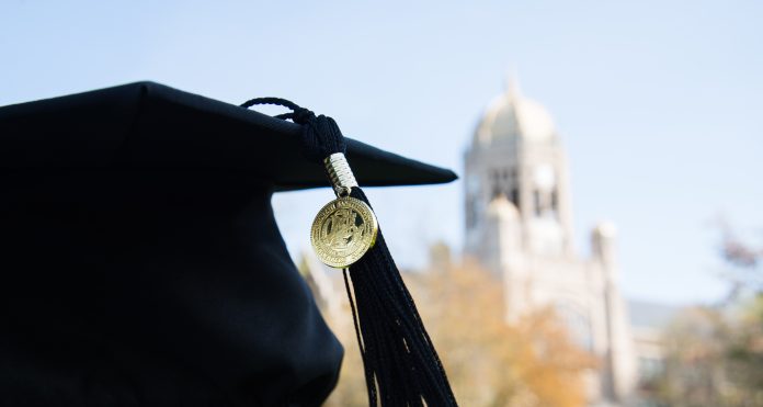 A black graduation cap is pictured in the foreground. In the background is Haas, the bell tower on Muhlenberg's campus.